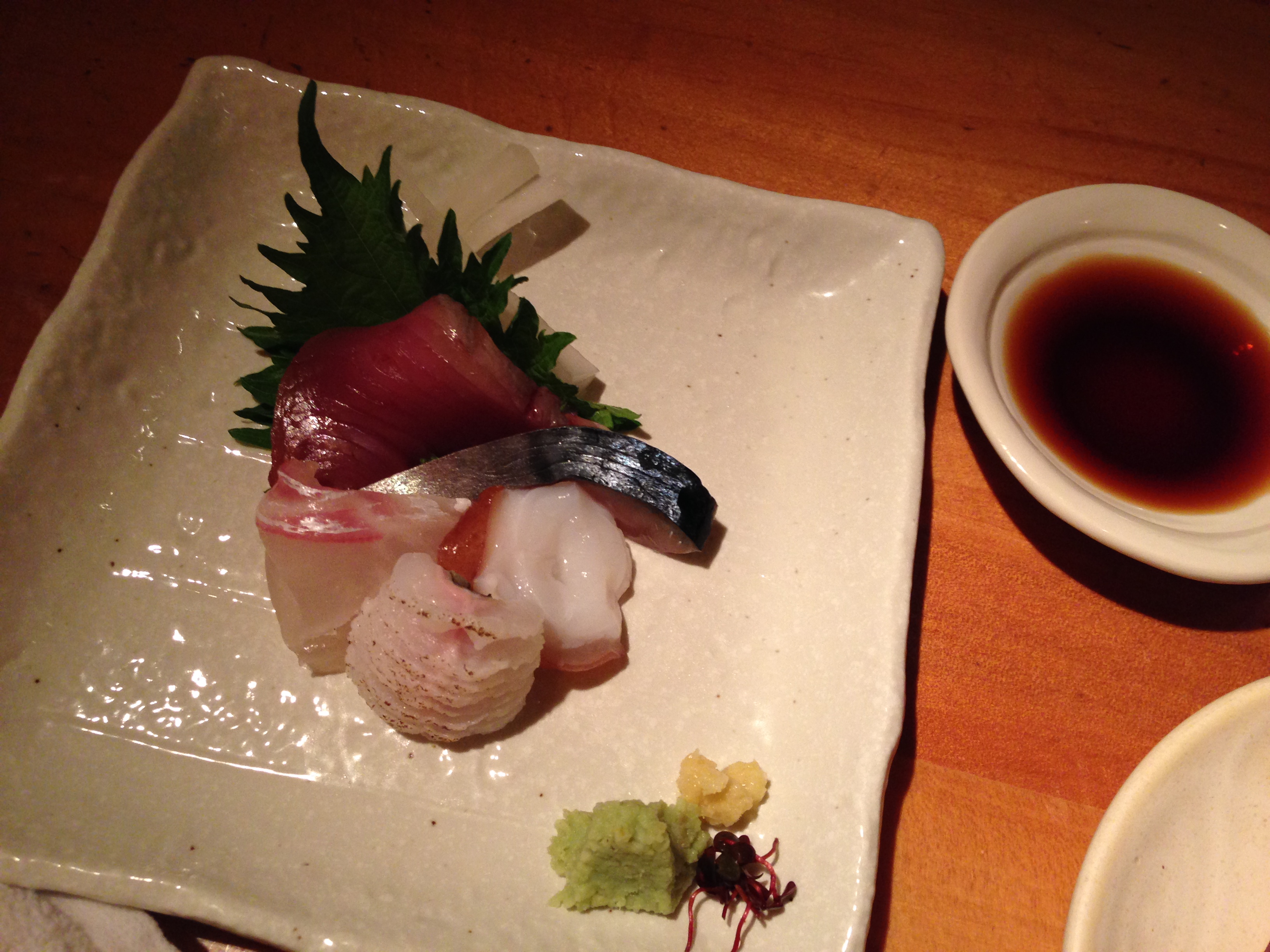 Three kinds of sashimi on a square plate with shiso, wasabi, and ginger