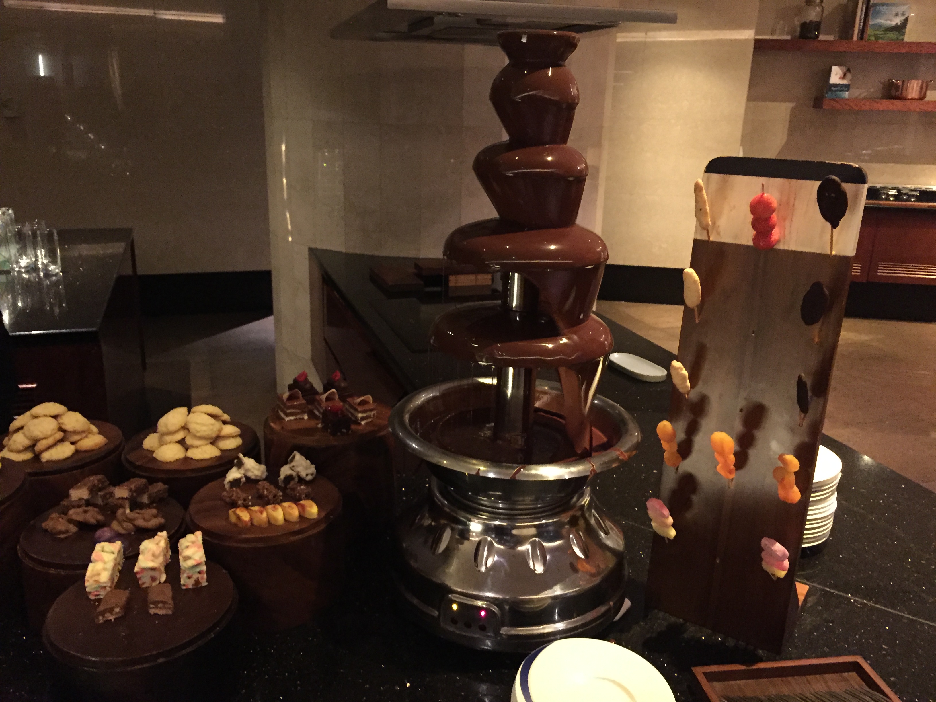 Floor-to-ceiling windows on two sides of a corner overlooking central Jakarta during the day — apartment towers, mid-rise buildings, palm trees, and a hazy sky
