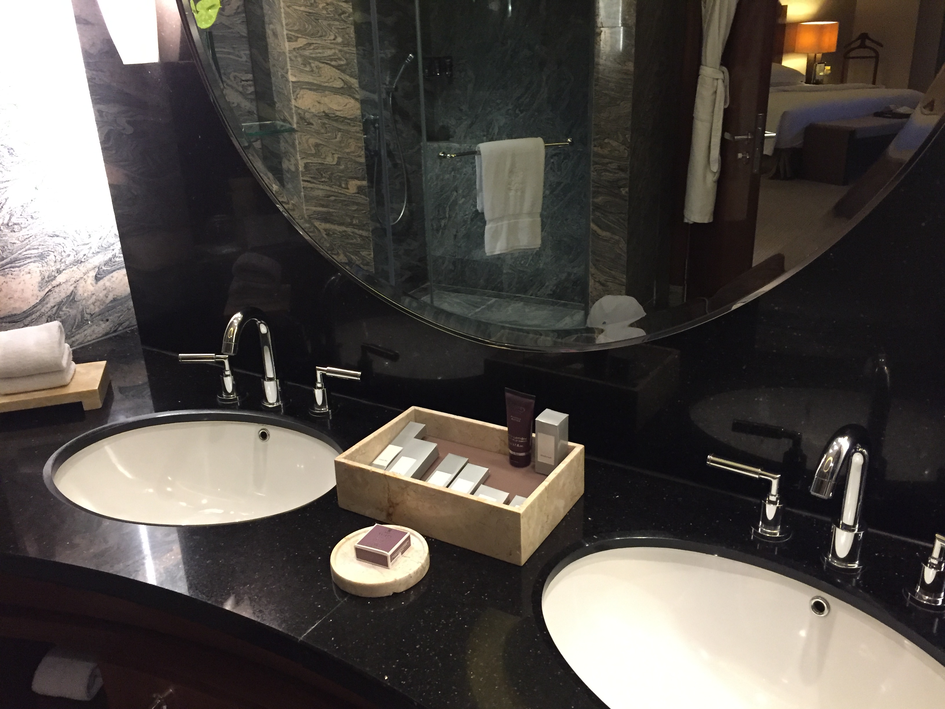 Double vanity with twin basins, a rectangular tray of toiletries, and a circular mirror